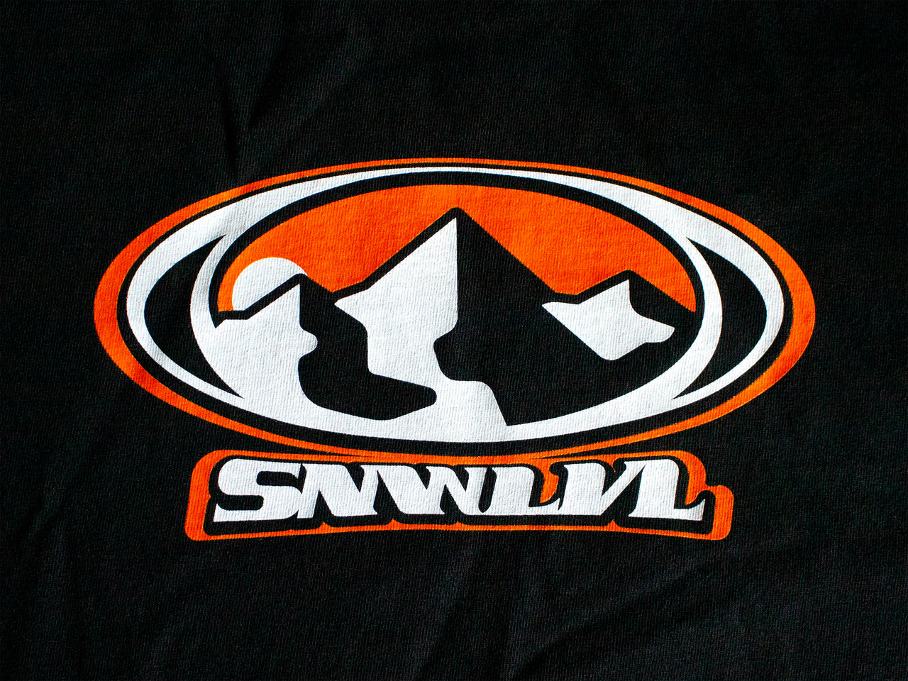 Detailed close-up of nostalgic Y2K mountain logo on premium thick cotton tee, black fabric with orange outlined peaks and oval border design